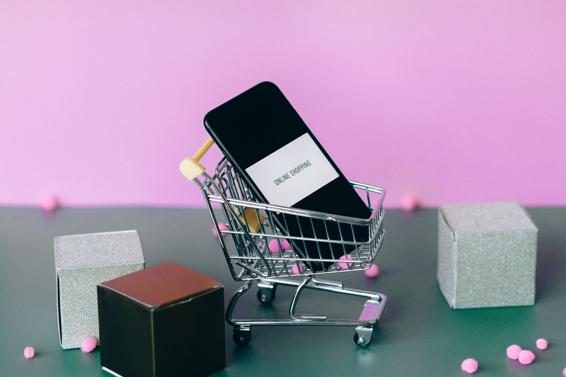 A smartphone with a shopping cart depicting the concept of online shopping in a colorful studio setup.